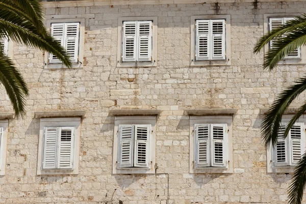 Stony vägg och vita fönster — Stockfoto