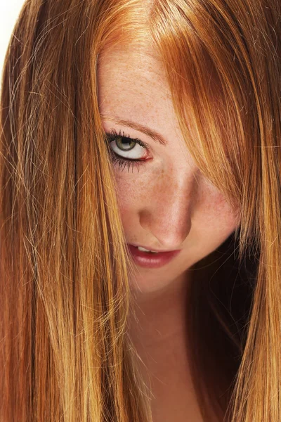 Junge rothaarige Frau schaut durch ihre Haare — Stockfoto