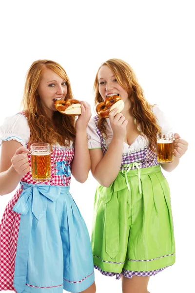 Two bavarian dressed women eating pretzels — Stock Photo, Image
