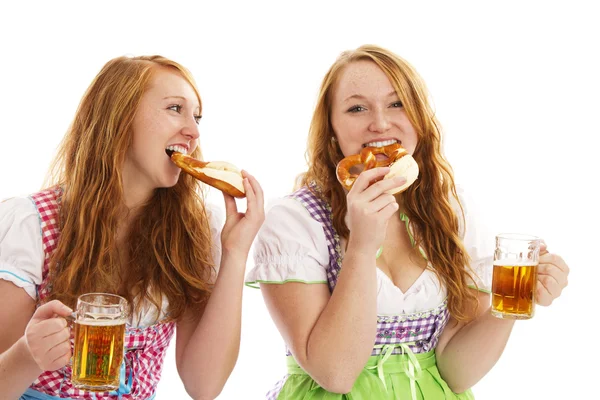 Two bavarian women eating pretzels and holding beer — Stock Photo, Image