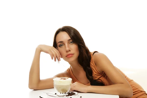 Beautiful woman bending over cappuccino on a table — Stock Photo, Image