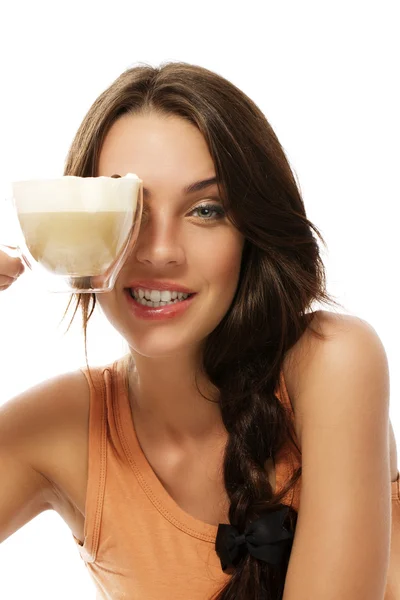 Krásná žena drží pohár s cappuccino káva nad její oko — Stock fotografie
