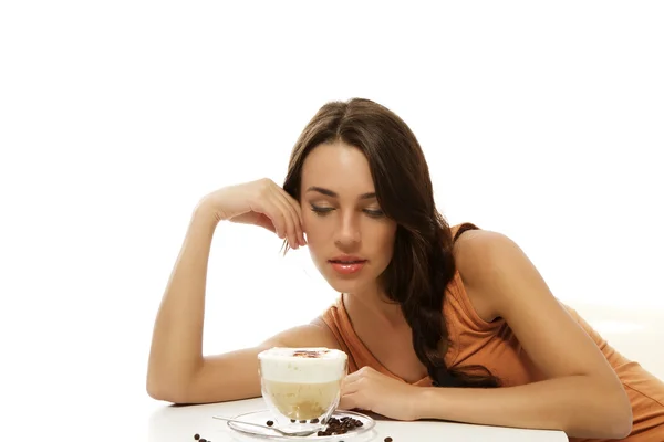 Krásná žena při pohledu na cappuccino káva před ní na stole — Stock fotografie