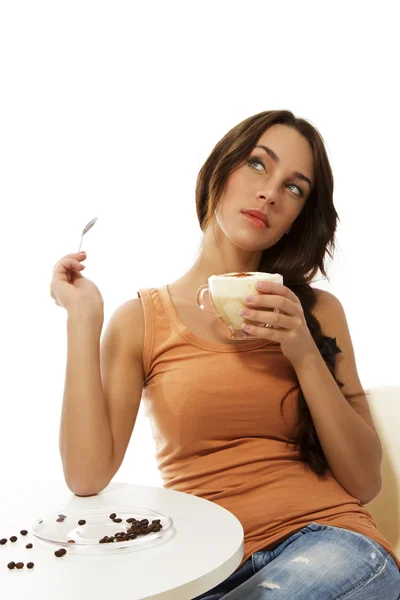 Zamyślona kobieta z cappuccino, siedzi przy stole — Zdjęcie stockowe