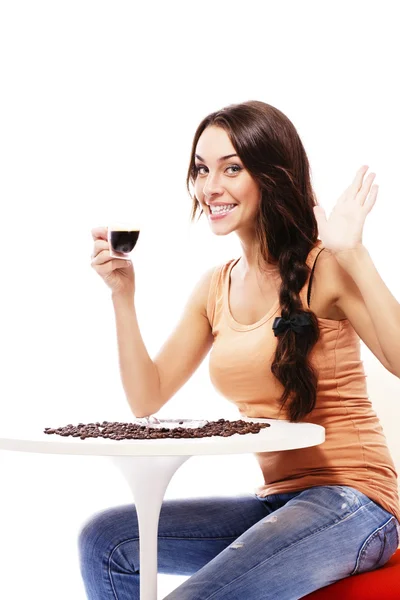 Szczęśliwa młoda kobieta siedzi przy stole trzymając kubek kawy espresso — Zdjęcie stockowe