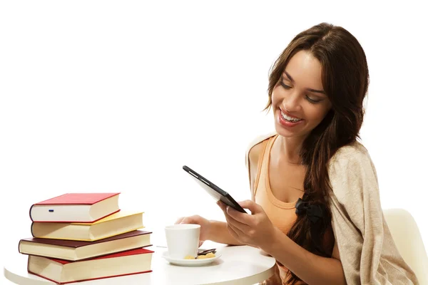Happy young woman reading ebook near books — Stock Photo, Image
