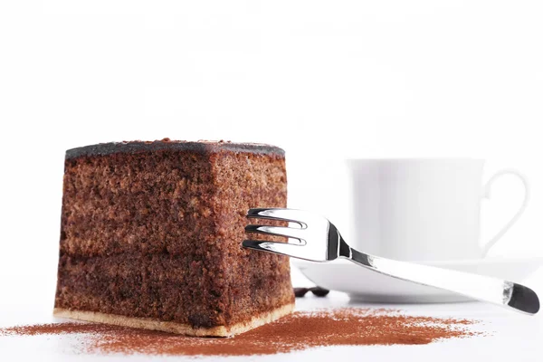 Ciasto czekoladowe z widelcem i filiżankę kawy w tle — Zdjęcie stockowe
