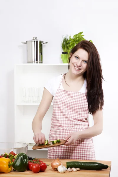Vrouw komkommer toe te voegen aan haar salade — Stockfoto