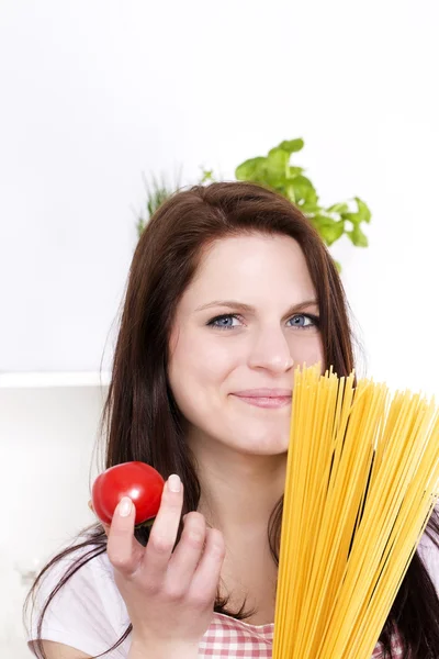 Leende kvinna anläggning pasta och tomat — Stockfoto