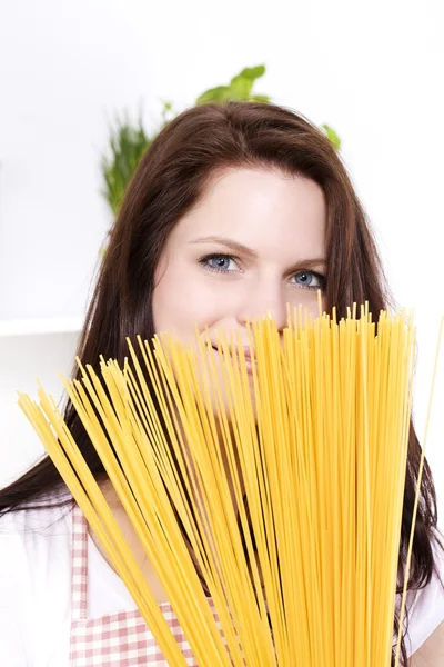 Jonge lachende vrouw is verstopt achter pasta — Stockfoto