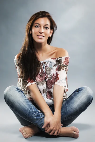 Young woman wearing blue jeans sitting on the floor — Stock Photo, Image