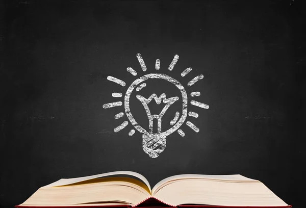 Bulb symbol and text book on blackboard background — Stock Photo, Image