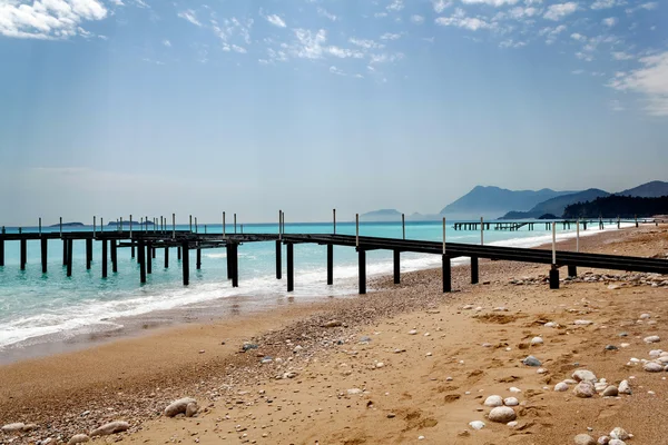 Beach with pier at the mediterranean sea — Stock Photo, Image
