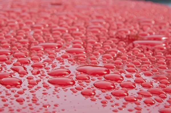 赤色サーフェス上の水液滴テクスチャ ロイヤリティフリーのストック写真