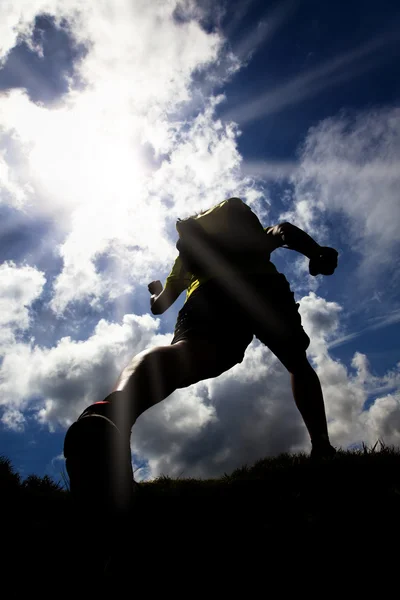 Sylwetka Runner na polu trawa tło światło słoneczne — Zdjęcie stockowe