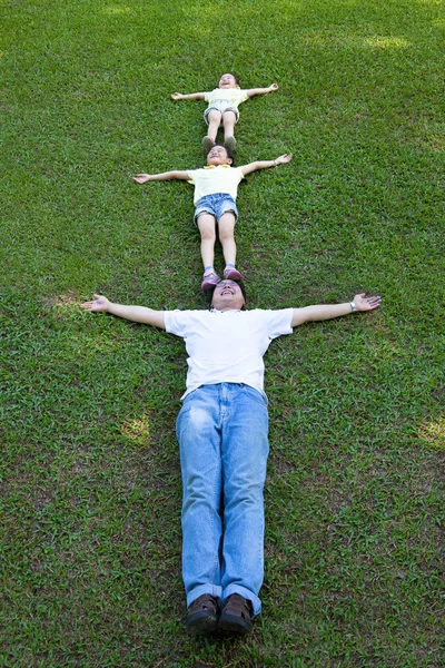 Família feliz deitada na grama — Fotografia de Stock