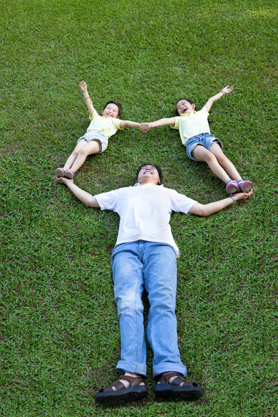 Feliz asiático familia mintiendo y jugando en la hierba — Foto de Stock