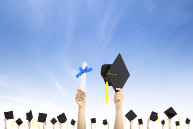 Hand holding graduation hats and diploma certificate with cloud background clipart