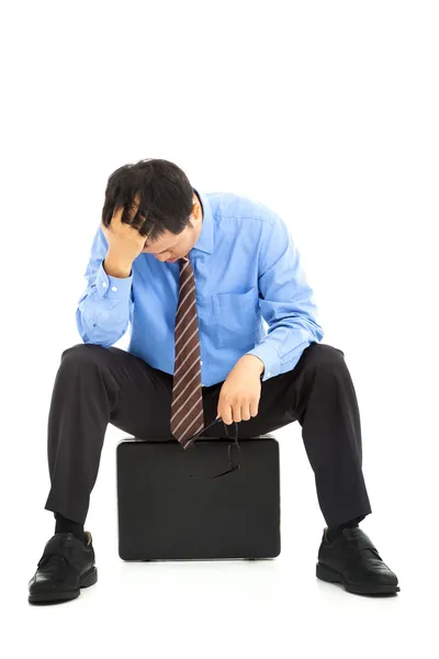 Расстроенный бизнесмен, сидящий на портфеле — стоковое фото
