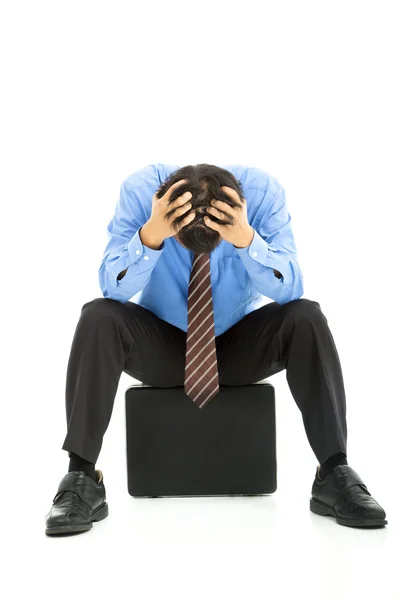 Business man sitting on briefcase with headache Stock Photo