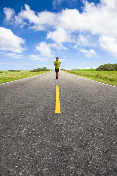 Mladý muž běží na prázdné silnici v létě — Stock fotografie