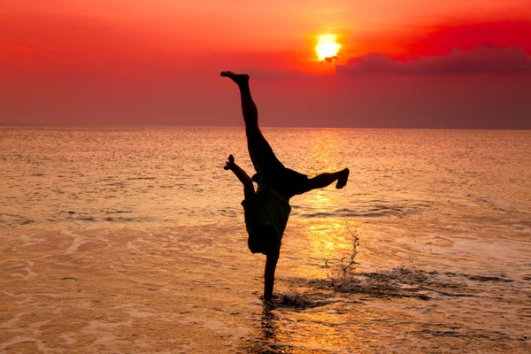Jonge man hand staan op het strand bij zonsondergang — Stockfoto