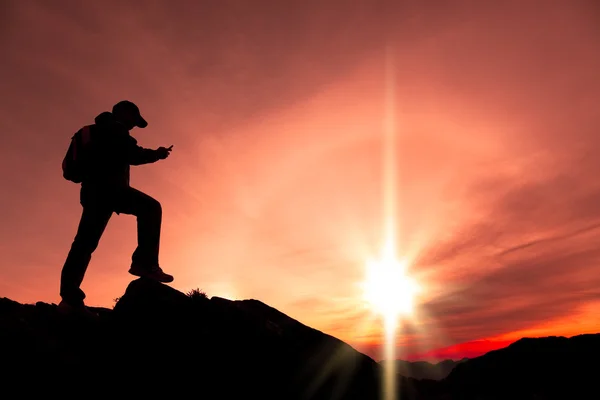 Молодой человек использует смартфон на вершине горы — стоковое фото