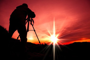 Silhouette of photographer on the top of mountain clipart