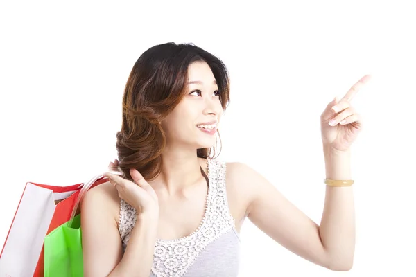 Счастливая молодая женщина с мешком для покупок указывает что-то — стоковое фото
