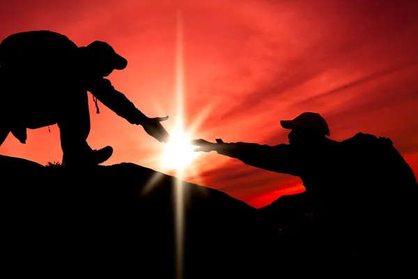 Silhouette di mano di aiuto tra due scalatori — Foto Stock