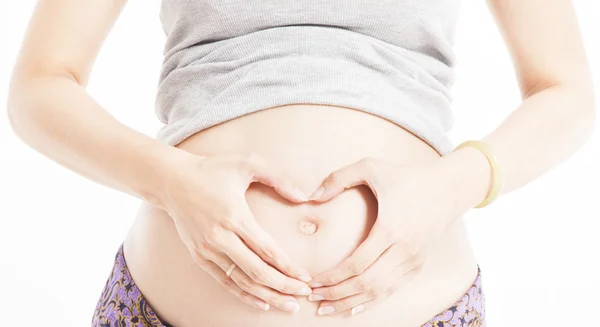 Těhotné břicho s mámou provedení tvaru srdce s rukama — Stock fotografie