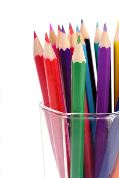 Lápis coloridos em um copo de vidro em um fundo branco — Fotografia de Stock