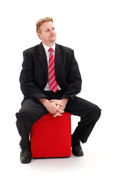 Επιχειρηματία που κάθεται στο κόκκινο ταμπουρέ — Φωτογραφία Αρχείου