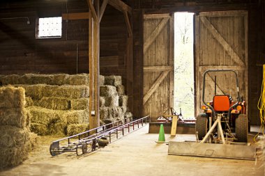Barn interior with hay bales and farm equipment clipart