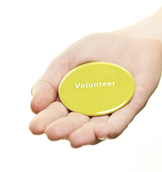 Hand holding vrijwilliger knop — Stockfoto