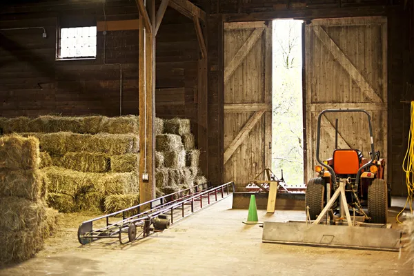 Interior del granero con fardos de heno y equipo de granja Imagen De Stock