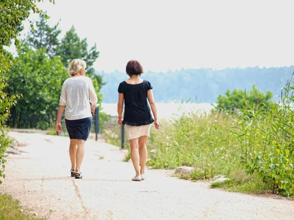 stock image Couple of women walking while talking on a gravel road at summer