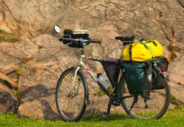 Loaded touring bicycle on rest break, next to a mauntain clipart