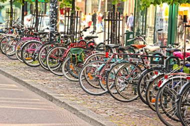 Bikes parked in the city, in a nice line into a rack clipart