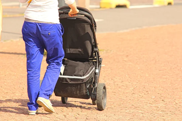 Genitore fare una passeggiata con un passeggino per bambini, sul pavimento di piastrelle in città — Foto Stock