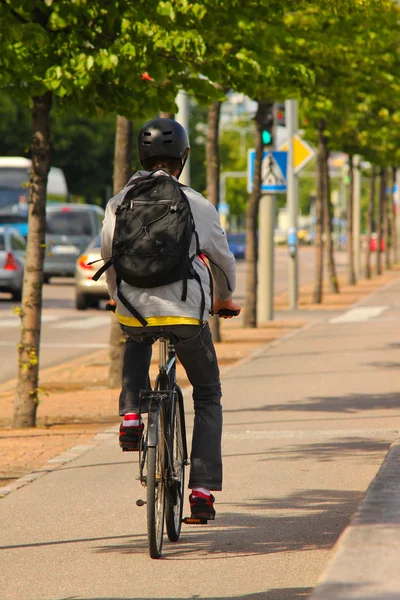 Rowerzysta na bocznej ulicy, w centrum miasta z pomiędzy drzew — Zdjęcie stockowe