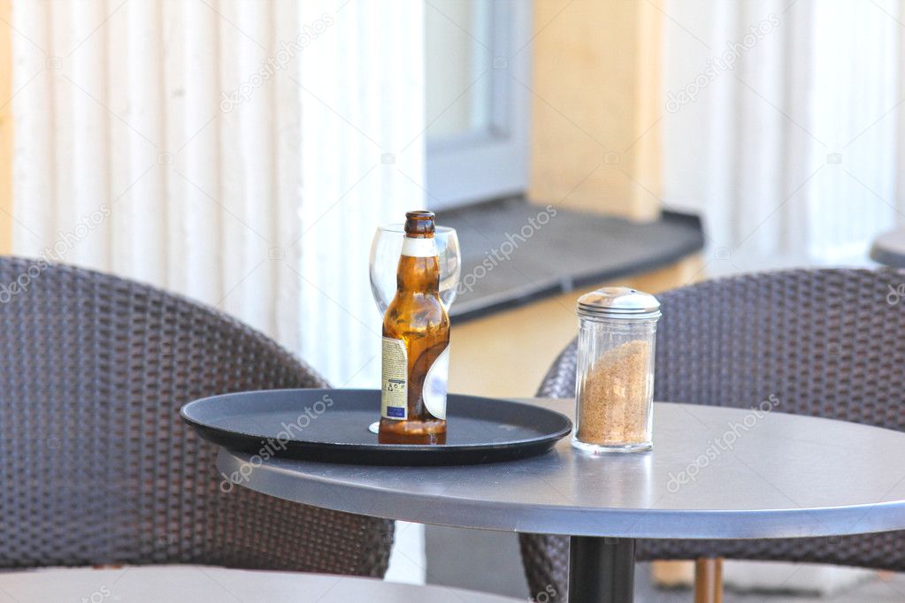 Restaurant outdoors, beer bottle on table, nobody around