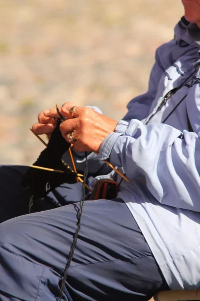 Femme âgée tricotant un tapis à l'extérieur, assise — Photo