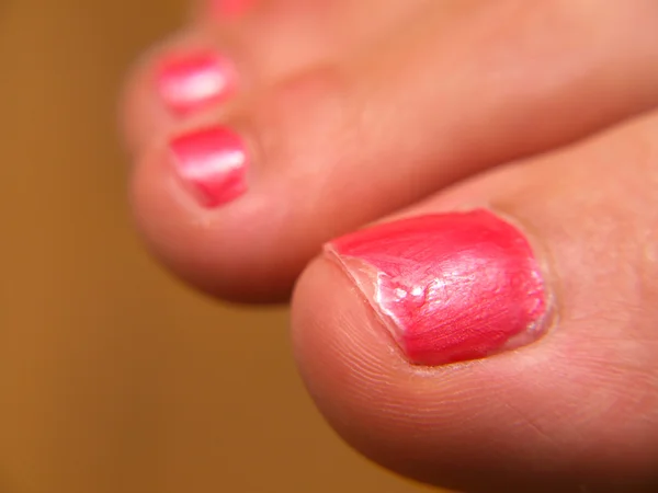 Primo piano di vernice per unghie rosa, sui piedi, pedicure — Foto Stock