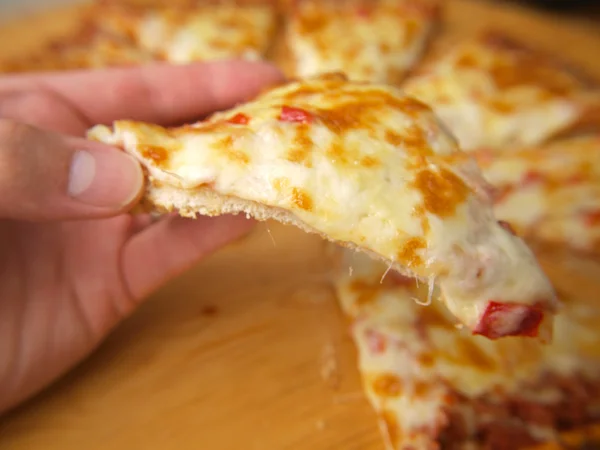 Slice of pizza, held up by a person — Stock Photo, Image