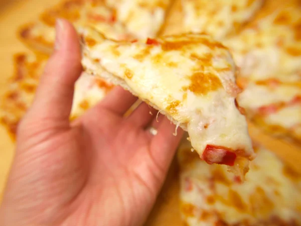Scheibe Pizza, die von einer Person hochgehalten wird — Stockfoto