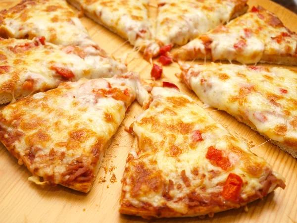 Pizza fresca en rodajas con pimiento rojo sobre tabla de madera —  Fotos de Stock