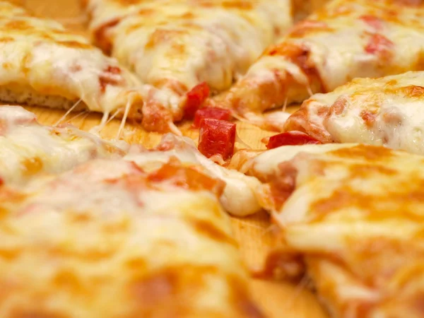 Нарезанная свежая пицца с красным перцем на деревянной доске — стоковое фото