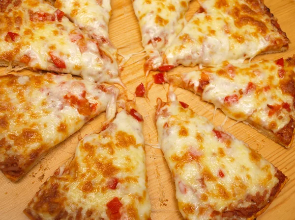Нарезанная свежая пицца с красным перцем на деревянной доске — стоковое фото