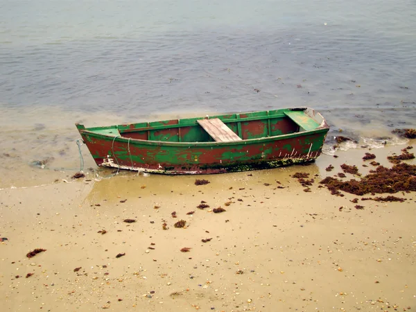 Kleine houten boot verankerd op het strand Stockfoto
